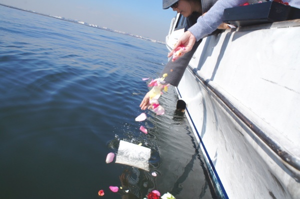 海洋散骨の様子。粉状にした遺骨を水に溶ける紙に包み、花とともに沖合の海にまく