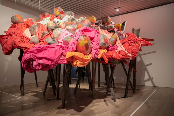 本展で最初に展示されるフィリダ・バーロウ（1944年、英国生まれ）の大型彫刻作品。工業用材料や色鮮やかに着彩されたキャンバスを、高さの異なる28本の脚が支えている。展示風景より『アンダーカバー2』（2020年）