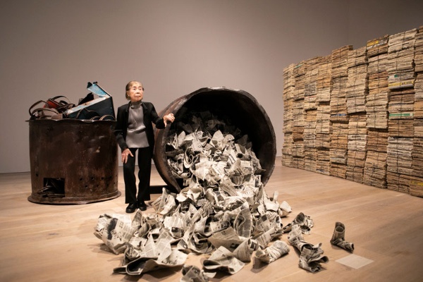 新聞を陶で表現した立体作品の横に立つ三島喜美代（1932年、大阪府生まれ）。自身の創作を「ごみを一生懸命作っています」と表現する。「命を懸けて遊んでいるっていう感じですね」
