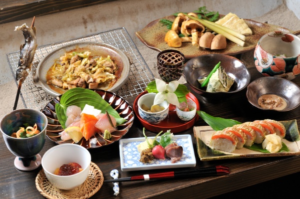 囲炉裏で焼く川魚と山菜の恵み、紅鱒の棒寿司、新鮮なお造りなどごちそう満載の夕げ