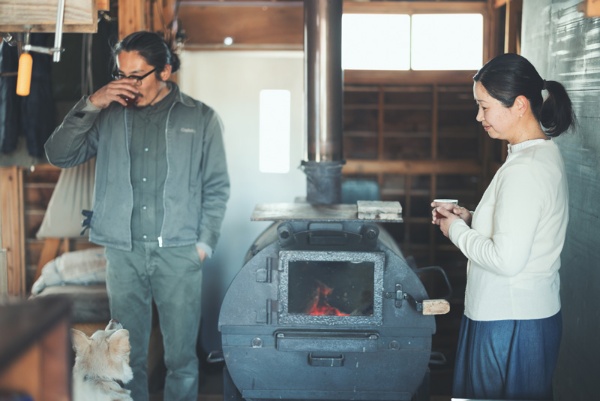 古材を使って店舗や住宅などの空間をリノベーションする、「大工仕事もする1級建築士」の夫・徳永青樹さんと。暖房にも調理にも活躍するまきストーブは、溶接をなりわいとする地元の知り合いの手作り