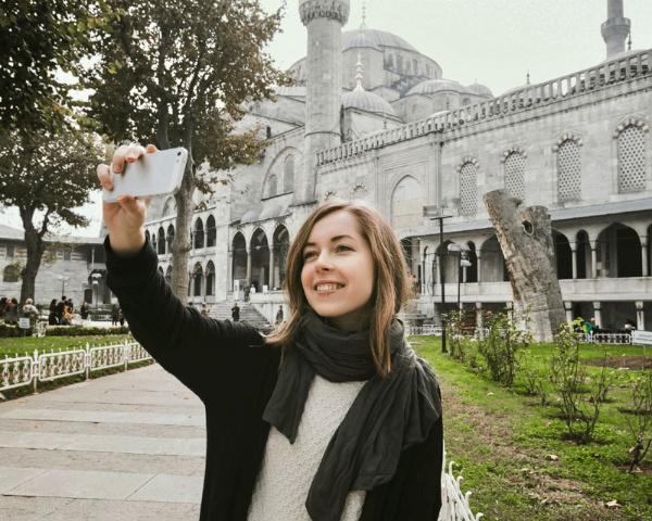 モスクを背景に撮影するトルコのツアーガイド、オズレム・エルジャンさん。昨年結婚したばかりで、新居のローンも残る中で観光客がいなくなる状況に直面した