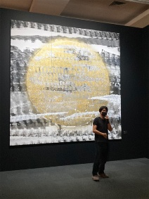 上野の森美術館で開催された「長坂真護展 Still A “BLACK” STAR」で展示された『月』の前で話す長坂さん。2000万円の値を付けた『真実の湖』など、電子ゴミを使って制作した作品が多数展示された