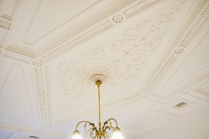 〈左〉当時の床の寄木細工を修復して再利用。　〈右〉天井の漆喰装飾は当時の写真をもとに修復・再現されている。