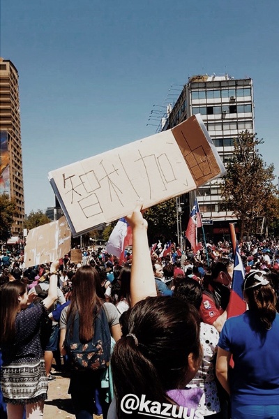 先日チリの反政府デモに参加した。手に持つのは「チリ、頑張れ」と中国語で書いたプラカード。香港出身なので中国語で書いてみた