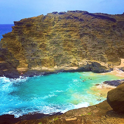 ハワイにあるこのシークレットビーチ。高台から、ぐるりと囲んでいる大きな岩壁を捉えることで、このビーチの良さや特徴が伝わります