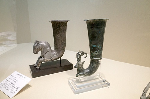 手前：銀製馬装飾リュトン、奥：青銅製山羊装飾リュトン。