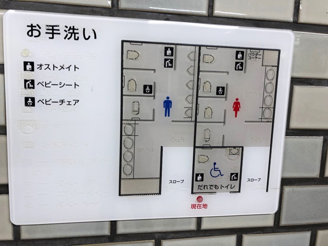 トイレの案内表示。どちらも入り口がスロープになっており、ベビーカーには優しい設計。案内では男女別のトイレに「ベビーシート」設置の表示があるが、実際にはベビーシートの代わりに、フットボードが設置されている