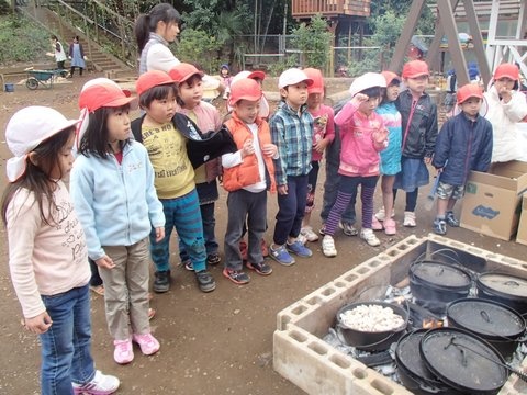 園庭にかまどを作って、子どもたちと焼き芋。みんなで一緒に焼けるのを待つ