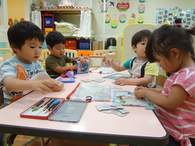 2歳児の部屋で子ども達はお絵かきやパズルなど、めいめいに夢中で遊ぶ