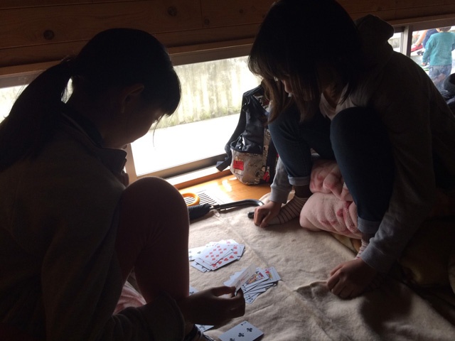 体育館の隅でトランプをして過ごしている女の子達。避難所で騒ぐと怒られることもあるという