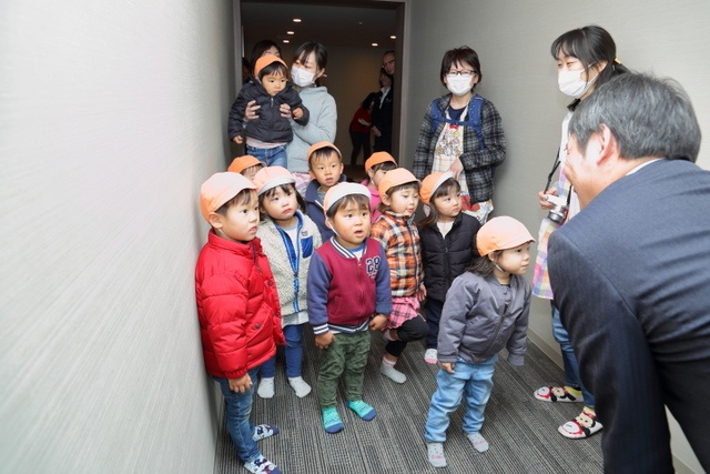 モデルルームの入り口で山本さんの説明を聞く子どもたち。目を見開いて真剣な表情です